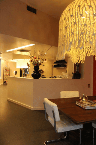 Het ontvangstgedeelte van de salon met een grote lamp boven een houten tafel